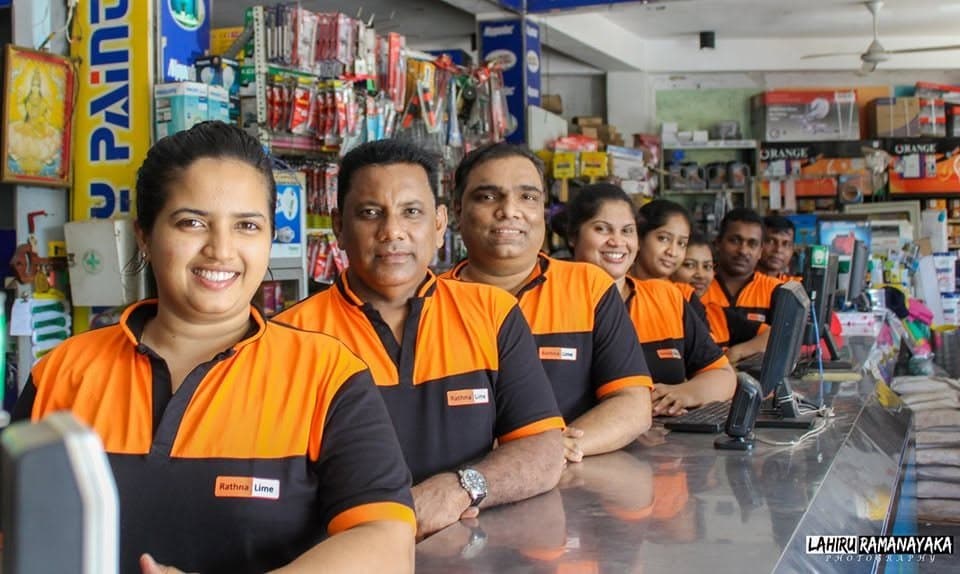 Rathna Lime staff behind the counter, with hardware stock on the shelves